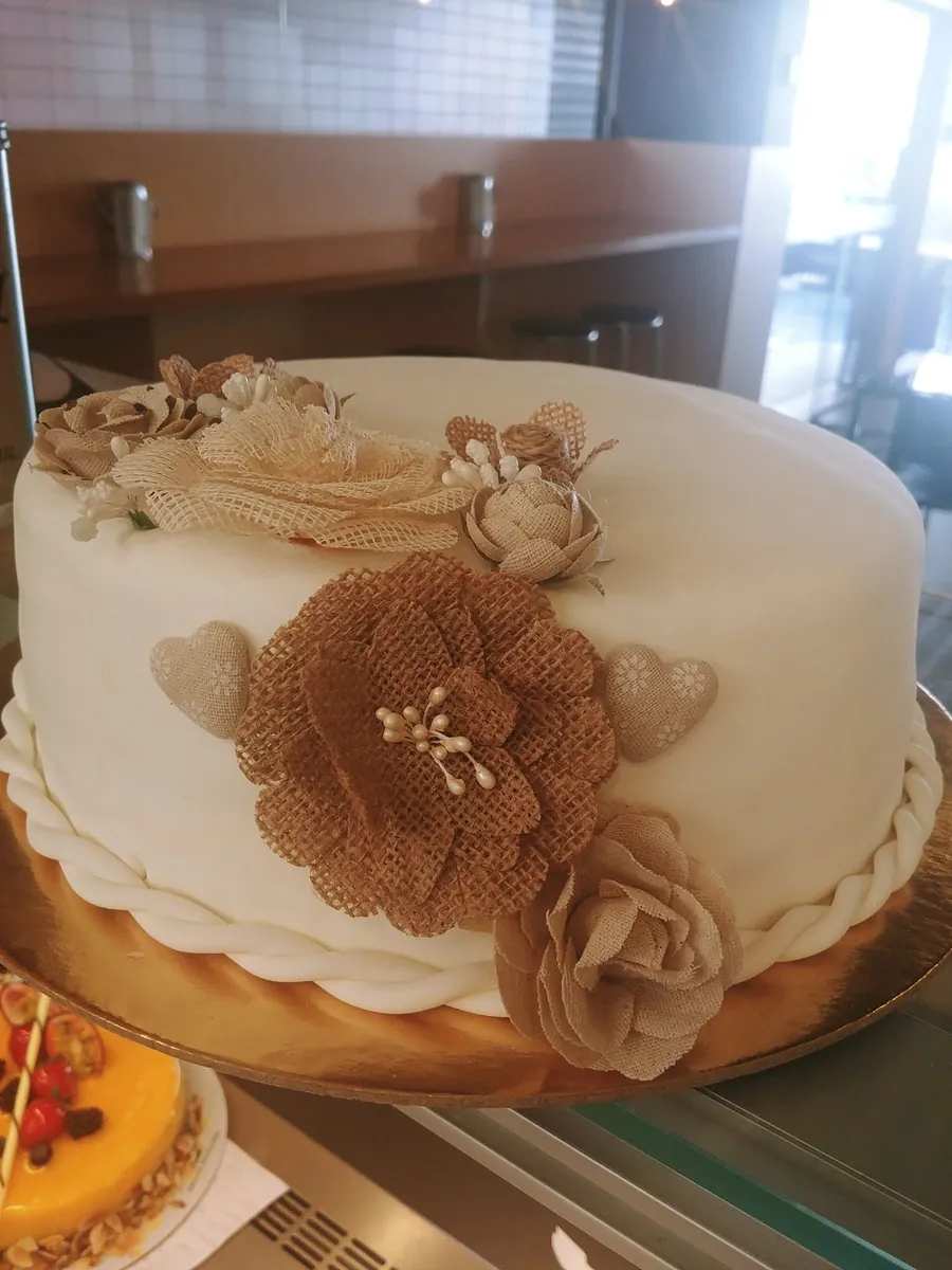 Bolo elegante com flor em tecido comestível, apresentado em evento